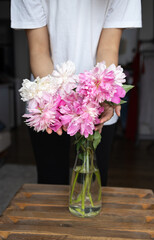 woman puts peonies flowers in vase. Housewife enjoying decor and interior of kitchen. Sweet home. Allergy free.