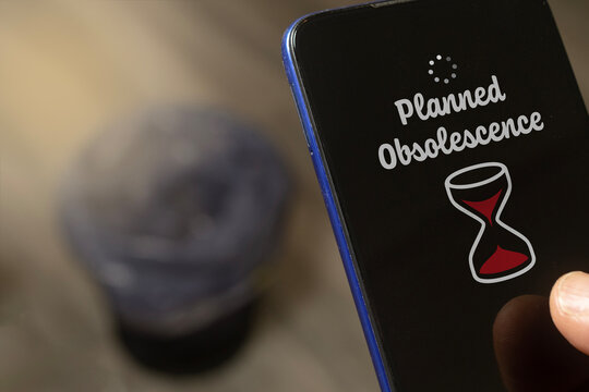 Planned obsolescence concept: man hold a phone above a trash bin