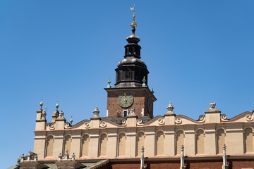 Fototapeta premium Main Square Market in Krakow, Poland. Town Hall Tower or Wieża Ratuszowa Kraków and the Cloth Hall Sukiennice, in the Old Town district of Cracow.