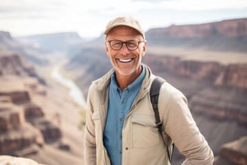 Close-up portrait photography of a glad mature man wearing a comfortable pair of jeggings against a scenic canyon background. With generative AI technology