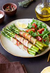 Asparagus baked with bacon and arugula and tomato salad. Healthy eating. Diet.