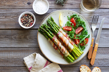 Asparagus baked with bacon and arugula and tomato salad. Healthy eating. Diet.