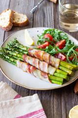 Asparagus baked with bacon and arugula and tomato salad. Healthy eating. Diet.