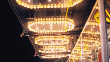 Golden illuminated defocused retro lamps decoration in amusement park. Festival atmosphere of funfair. Amusement park location background