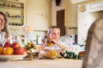 Blonde beautiful boy having breakfast with his family at the kitchen
