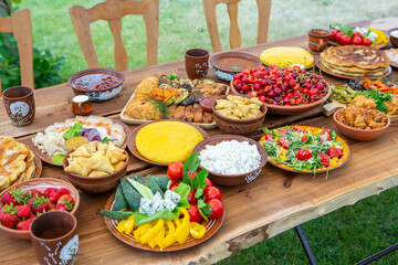 Homemade Romanian Food with grilled meat, polenta and vegetables Platter on camping. Romantic traditional moldavian food outside on the wood table.