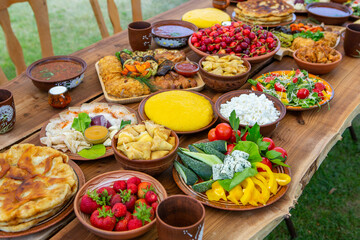 Homemade Romanian Food with grilled meat, polenta and vegetables Platter on camping. Romantic traditional moldavian food outside on the wood table.