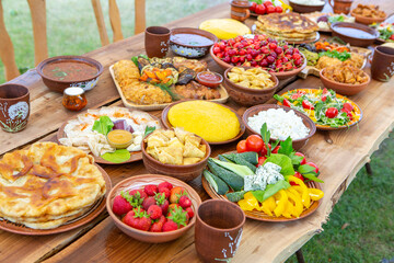 Homemade Romanian Food with grilled meat, polenta and vegetables Platter on camping. Romantic traditional moldavian food outside on the wood table.