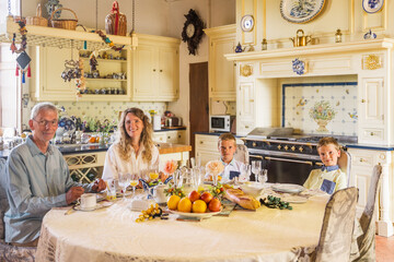 Two brothers, mother and grandfather sitting together during the breakfast at home