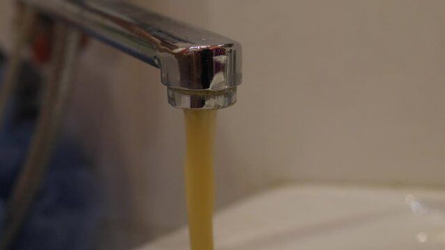 close-up from the faucet pouring dirty untreated yellow water, plumbing accidents, environmental disaster, pollution of drinking fresh water in the city
