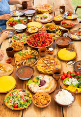 Homemade Romanian Food with grilled meat, polenta and vegetables Platter on camping. Romantic traditional moldavian food outside on the wood table.