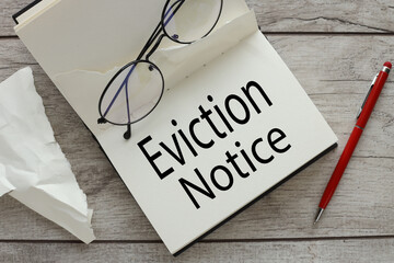 eviction notice. On the desktop is a red pen, an open notepad with the inscription. Text eviction notice. . business concept