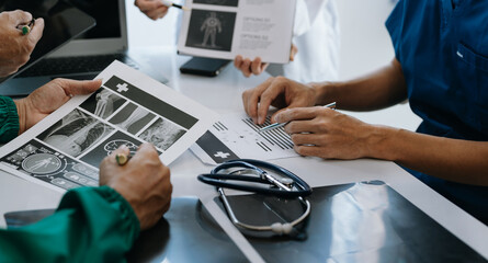 Medical team having a meeting with doctors in white lab coats and surgical scrubs seated at a table...