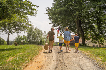 Back view of the grandfather, mother and two little boys walking together through the path