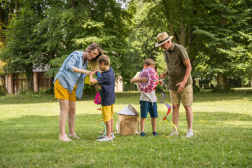 Fototapeta premium Full-length portrait of cheerful family with two kids playing with kite in the park