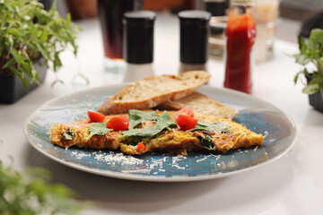 Veggie omelette with cherry tomato, cheese on a blue plate, selective focus. 
