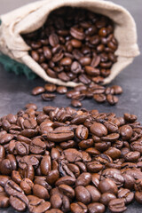 Heap of dark roasted fragrant coffee beans in jute bag