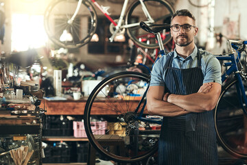 Fototapeta na wymiar Portrait, serious and repair man in bicycle shop with arms crossed in workshop. Face, bike mechanic and confident male person, professional or mature technician and glasses in store or small business