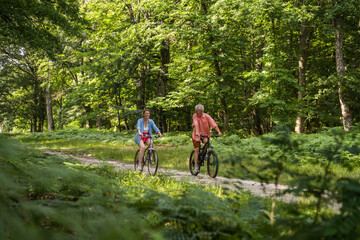 Fototapeta premium Senior father and daughter riding bicycles and communicating with each other