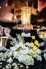 Composition flowers, candles, candlesticks on floor hall restaurant. Chairs for guests. Table setting, setup. Trendy decor large chandelier. Birthday, baptism, event. Details golden rich interior.