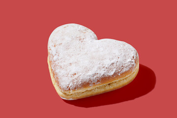 Heart shaped donut with glaze on red pastel background