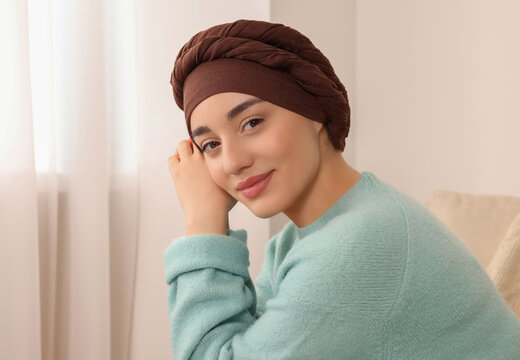 Cancer patient. Young woman with headscarf near window indoors