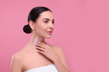 Naklejka premium Beautiful woman with smear of body cream on her neck against pink background, space for text