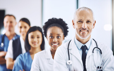 Smile, team and portrait of senior doctor with nurses in hospital, leadership and teamwork in healthcare. Health, diversity and confident doctors in group and happy medical employees in row together.