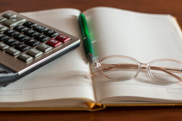 calculator, glasses, notebook and pen on accountant desk. financial chart report on office business table