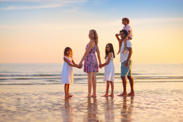 Family walking on tropical beach at sunset