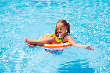 Child in swimming pool on toy ring. Kids swim.