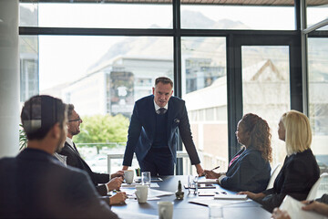 Presentation, man speaker with coworkers and in business meeting in a conference room of their workplace. Brainstorming or planning, ideas or data review and colleagues together in modern office
