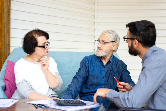 Confident bank manager consulting old senior couple clients at meeting sitting at home terrace. Pension planning, medical health insurance, buying property, closing deal with male bank specialist