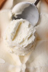 Scoop of delicious vanilla ice cream in container, closeup