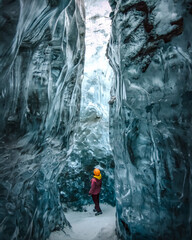 Exploring woman observes nature inside an ice cave
