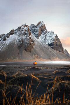A traveling couple enjoys incredible views of the mountains from a black beach in Iceland