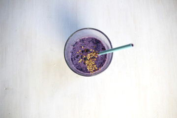 Smoothie glass with blueberry, linen seeds, milk on white background