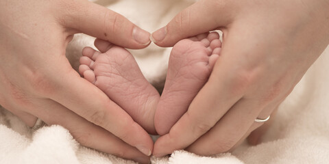 familiar hands and legs. happy mother forms a heart around the tiny  legs of her newborn tiny baby.