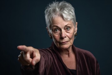Medium shot portrait photography of a glad mature woman raising a finger as if having an idea against a deep indigo background. With generative AI technology