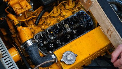 Engine of a boat that moves on diesel fuel. Adjusting the valves and maintenance on the yellow...
