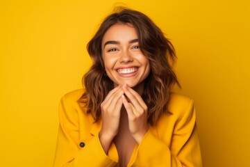 Headshot portrait photography of a grinning girl in her 20s making a heart with the hands against a bright yellow background. With generative AI technology