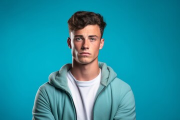 Fototapeta premium Headshot portrait photography of a glad boy in his 20s crossing the arms against a teal blue background. With generative AI technology