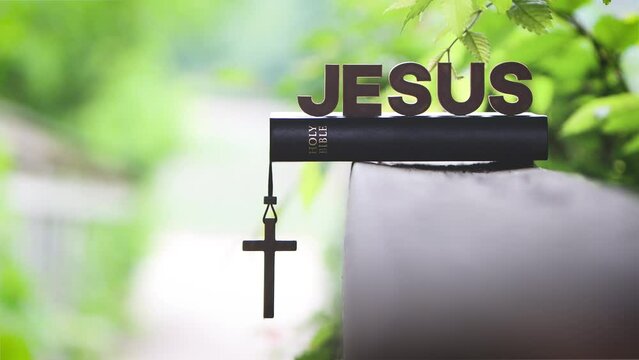 The word JESUS, the Bible, the Holy Cross of Jesus, the sound of birds in the forest, and trees swaying in the wind and nature background
