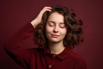 Fototapeta premium Headshot portrait photography of a glad girl in her 20s holding the hand on the forehead in a headache gesture against a burgundy red background. With generative AI technology