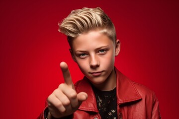Obraz premium Close-up portrait photography of a glad boy in his 20s making a rock on or rock horns gesture with the hand against a ruby red background. With generative AI technology