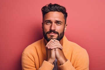 Headshot portrait photography of a satisfied boy in his 30s making a gesture of i'm cold hugging himself against a coral pink background. With generative AI technology