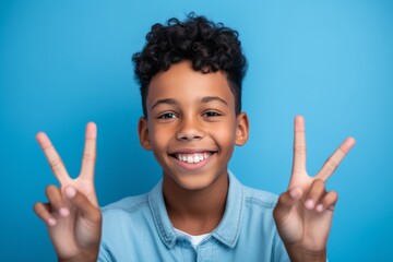 Close-up portrait photography of a happy boy in his 30s making a peace gesture with two fingers against a periwinkle blue background. With generative AI technology