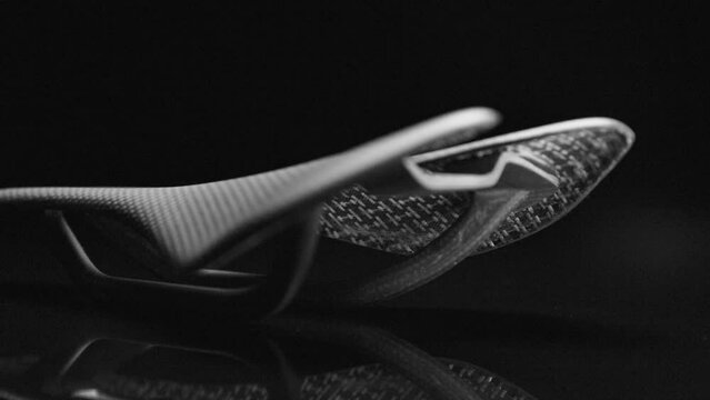 Black carbon road bicycle saddle on dark reflective background