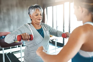 Deurstickers Fitness Coaching, dumbbell and fitness with old woman and personal trainer for support, health or physiotherapy. Training, weightlifting and workout with senior client and female trainer for elderly exercise