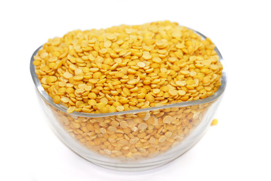 Yellow lentil in glass bowl isolated on white background with clipping path. To prepare a traditional vegetarian Indian spiced soup-puree chana dal.